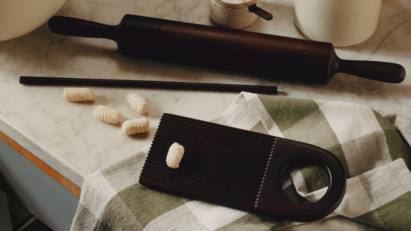 Rotating GIF of different lifestyle product images and interior shots of stylized homes. There is a gnocchi maker lifestyle image, a modern living room with a rug, a pink and purple sofa, etc.