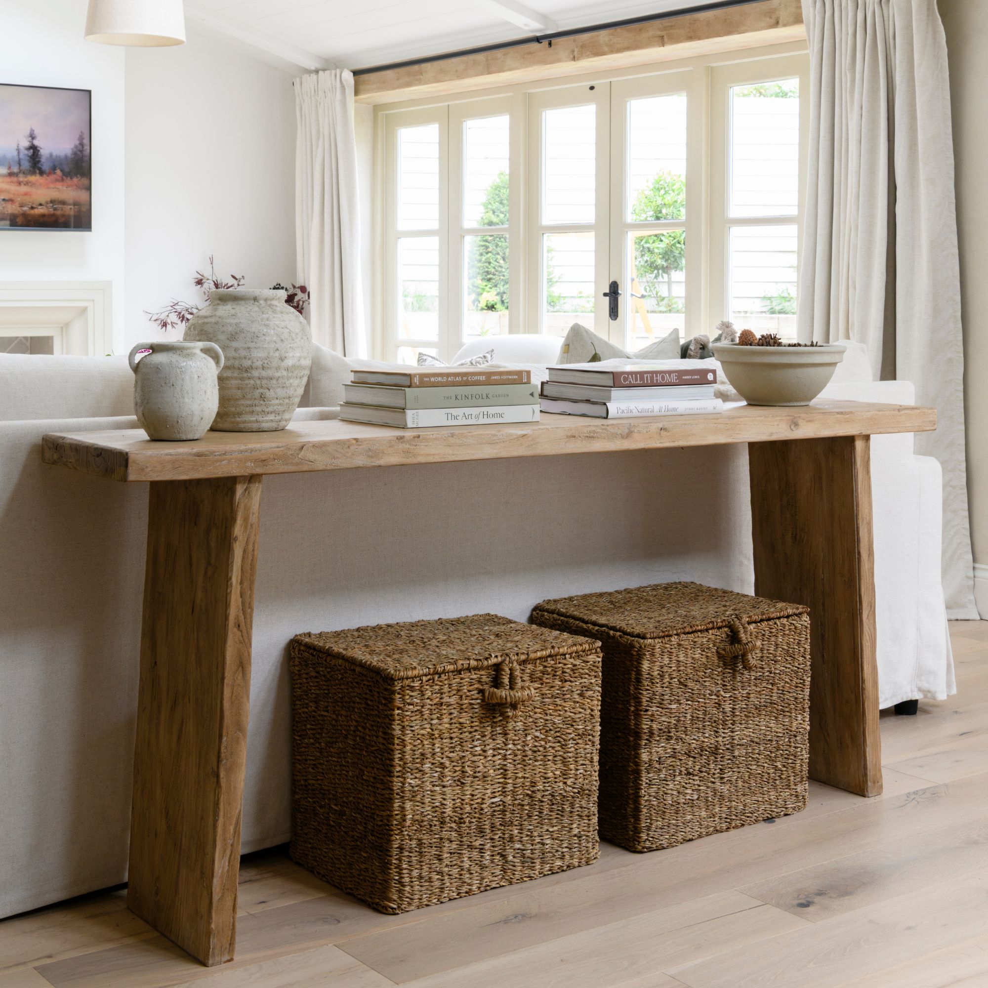 Console table in a neutral living room, with two large storage baskets sitting underneath it