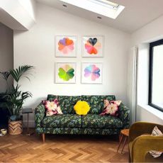 Living room with four colourful graphic art prints above green floral sofa