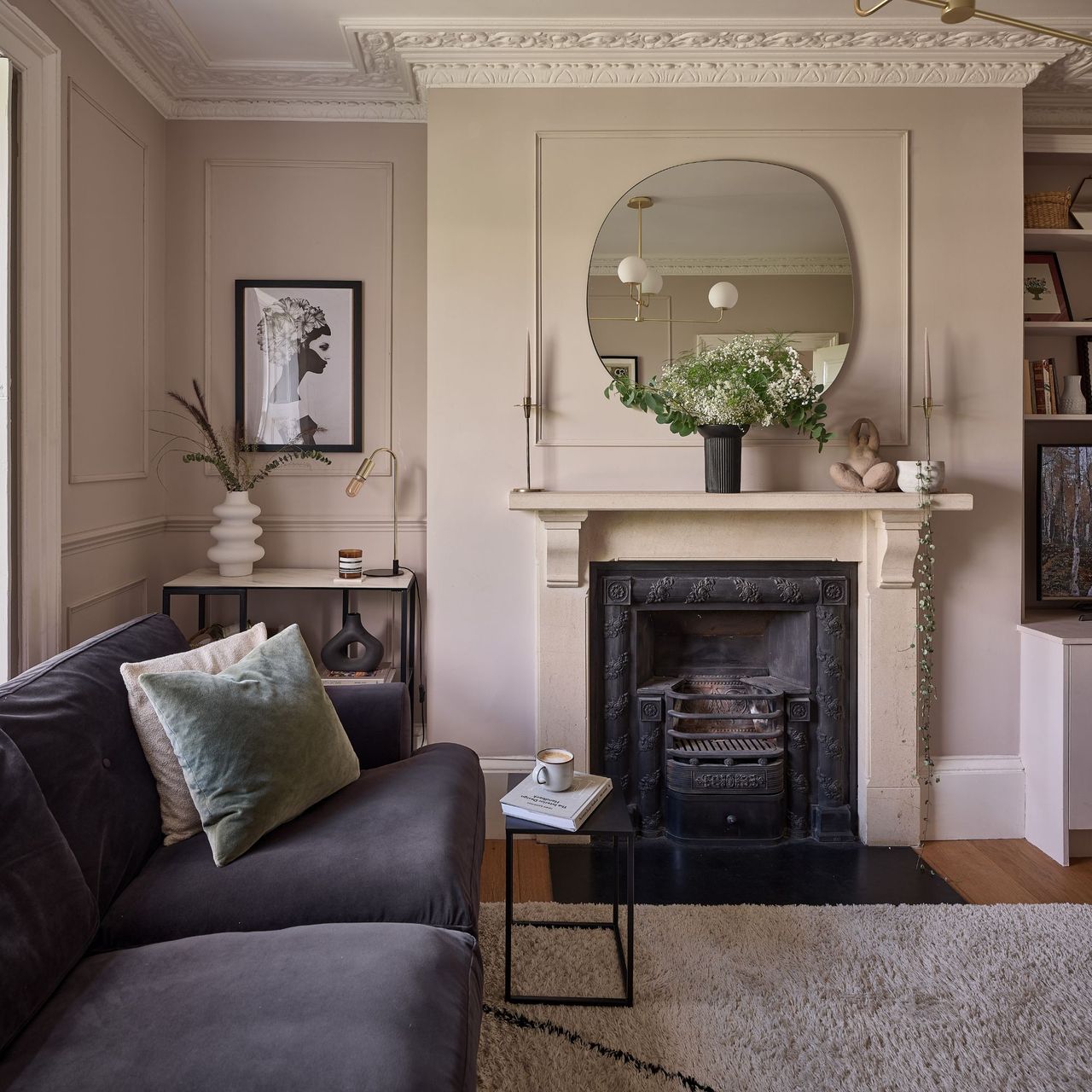 Pink living room with period features, an open fireplace with a mirror over it, and a grey sofa to the left