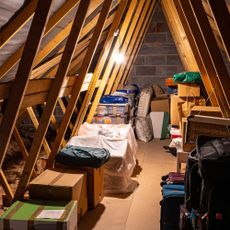 Items stored neatly on boards in between joists in a lit loft with a steeply pitched roof