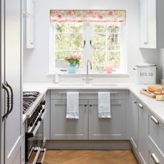 White painted galley kitchen with grey cabinets and a white worktop