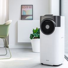 A portable air conditioner sat on the floor in a modern dining room 