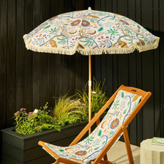 Habitat x Scion Jackfruit print parasol and deckchair in small courtyard garden with black fencing.