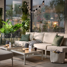 IKEA Plant stand on a patio. There is a large cream garden sofa, coffee table and green cushions.