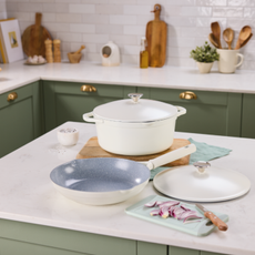 Aldi aluminium frying pan and casserole on a white kitchen island in a kitchen with white countertops and green cupboards.